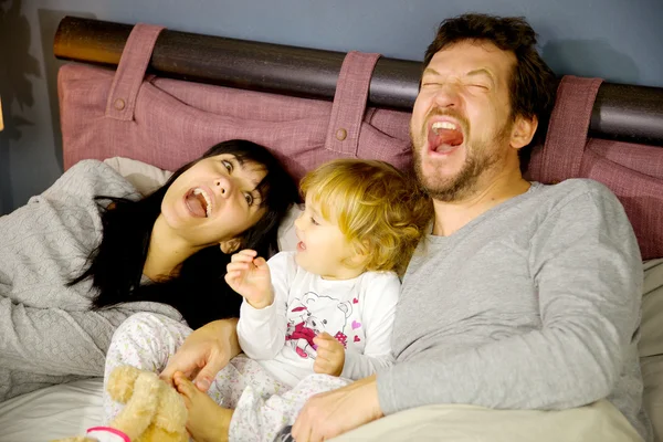 Joyeux famille riant au lit avec bébé fille — Photo