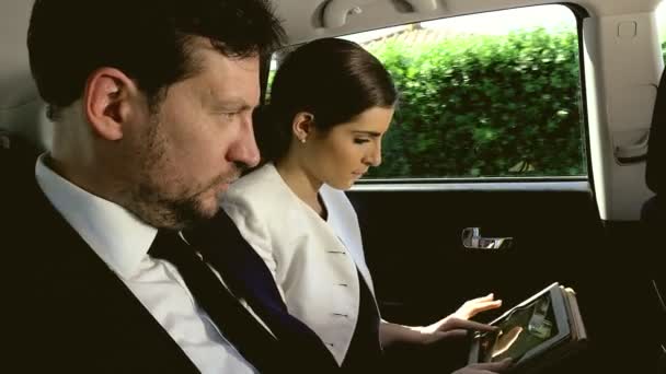 Mooie man en vrouw in limousine met technologie werkt tijdens het reizen — Stockvideo
