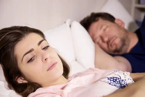 Frau im Bett mit Freund denkt über Beziehung nach, während der Mann in Großaufnahme schläft — Stockfoto