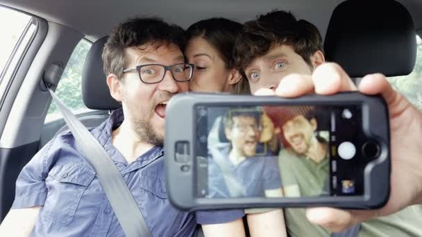 Tre glada vänner med selfie i bilen gör roliga grimaser 4k — Stockvideo