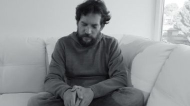 Üzgün adam kanepede oturuyor ve düşünceli.