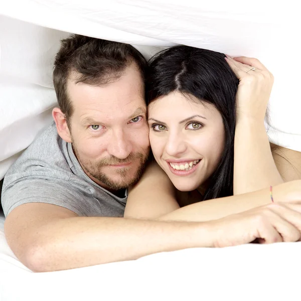 Couple amoureux souriant sous le drap de lit — Photo