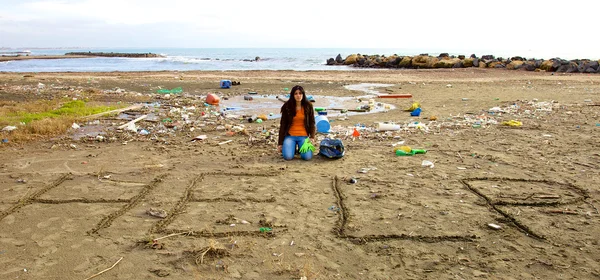 Triste écologiste demandant de l'aide assis sur la plage pleine de saleté — Photo