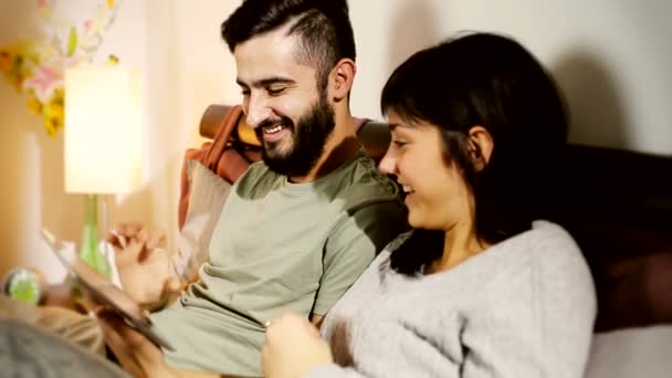 Pareja con tableta en la cama — Vídeo de stock