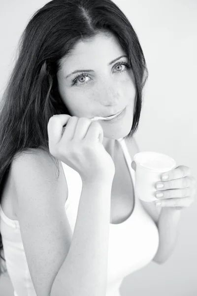 Brunette girl  eating white yogurt — Stock Photo, Image