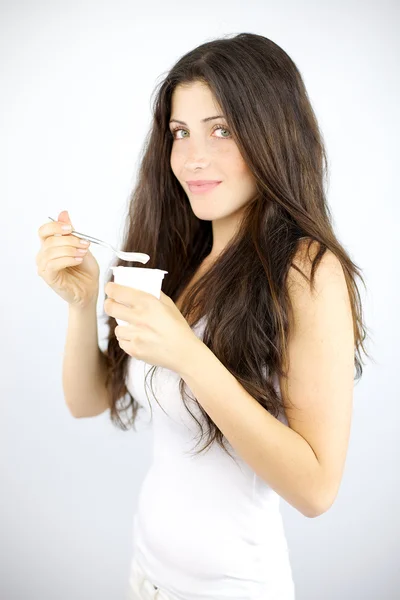 Brunette girl eating white yogurt — Stock Photo, Image