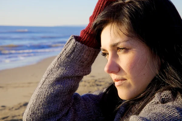 Triste jeune femme regardant coucher de soleil sur la plage en hiver — Photo