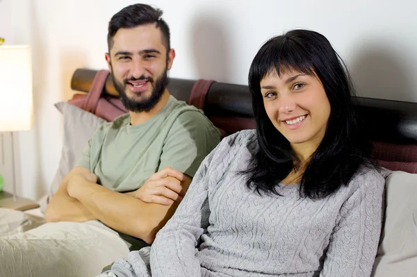 Smiling young couple in bed looking — Stock Photo, Image