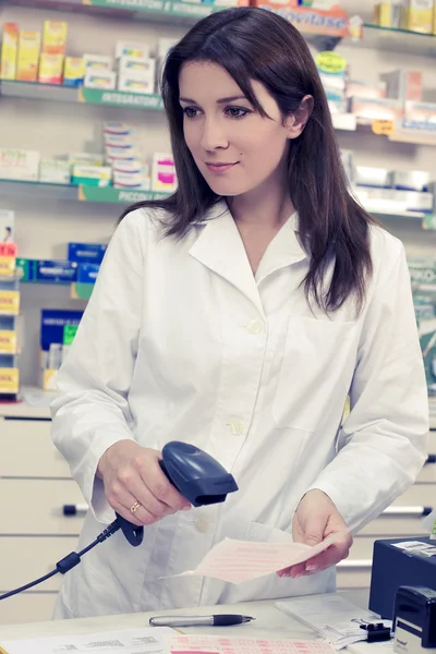 Vrouwelijke apotheker controleren voorschrift aan balie in winkel — Stockfoto