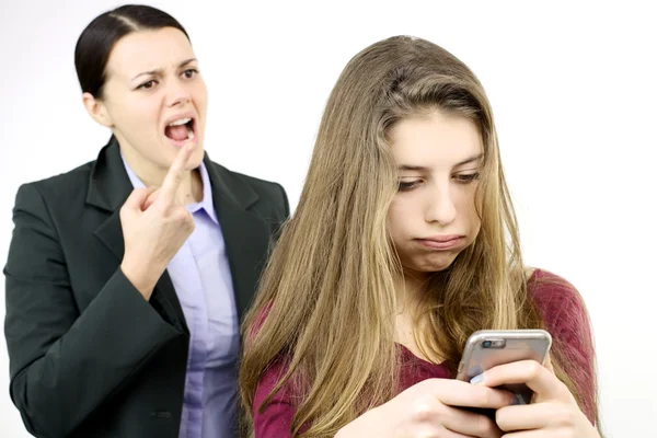 Dcera hraje s mobilní telefon, zatímco matka křičí Stock Obrázky