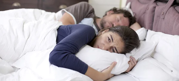 Traurige verzweifelte Frau im Bett, während Ehemann schläft — Stockfoto