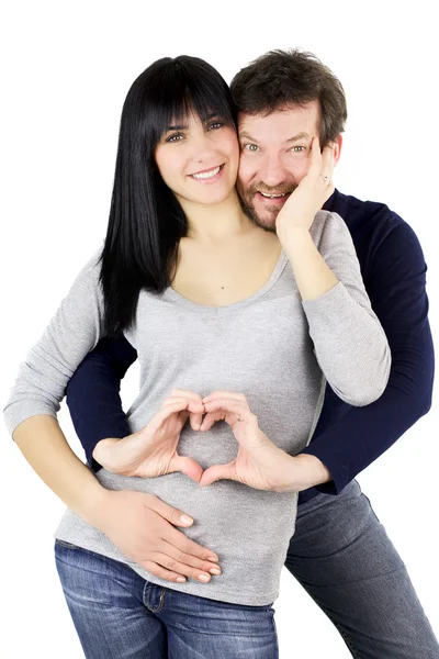 Casal europeu sorrindo abraçado mostrando sinal de amor na barriga grávida — Fotografia de Stock