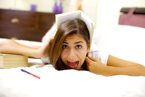 Flicka trött av att studera skrek av boken på huvudet — Stockfoto