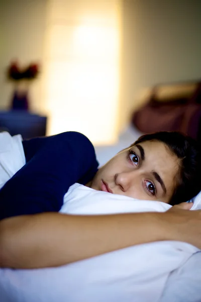 Mulher muito triste deitada na cama olhando câmera — Fotografia de Stock