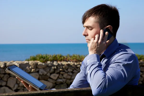 Hombre de negocios fresco que trabaja con la tableta y el teléfono al aire libre —  Fotos de Stock