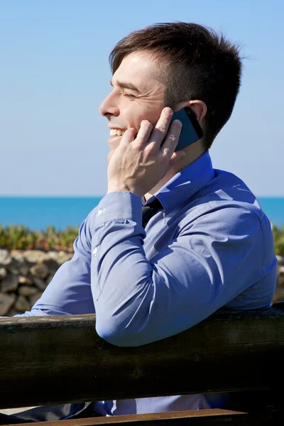 Heureux jeune homme d'affaires au téléphone souriant devant l'océan — Photo