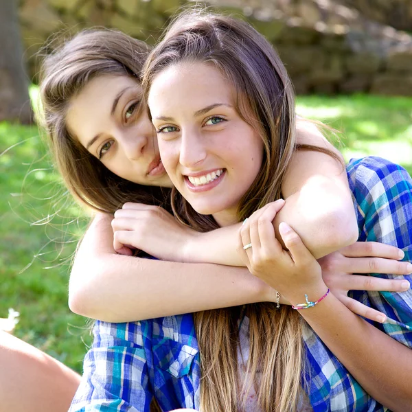 Two happy teenager girlfriends hugging in park looking camera — Stock Photo, Image