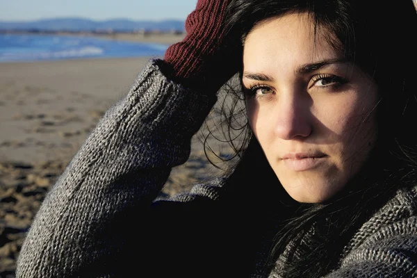 Sorgliga kvinna i vinter på stranden ser kameran — Stockfoto