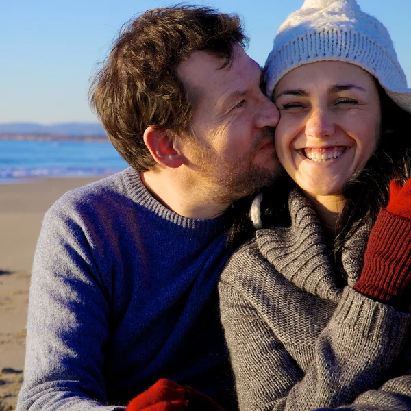 Happy man kissing girlfriend in front of beach in winter — Stock Photo, Image