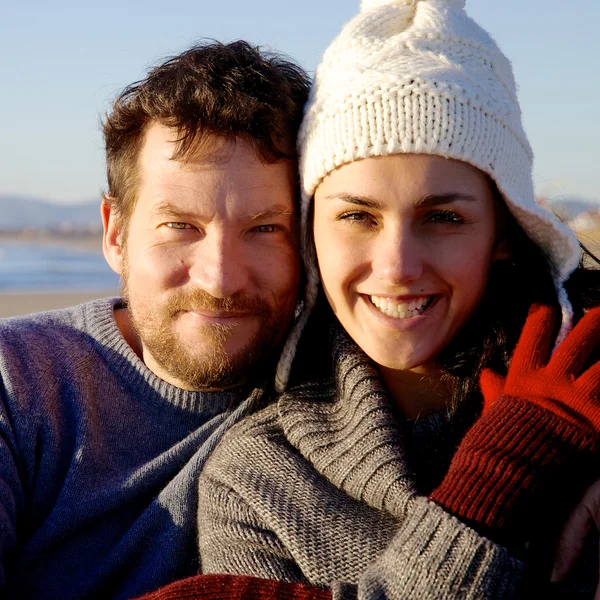 Felice coppia sorridente di fronte alla spiaggia alla ricerca di fotocamera durante il tramonto — Foto Stock