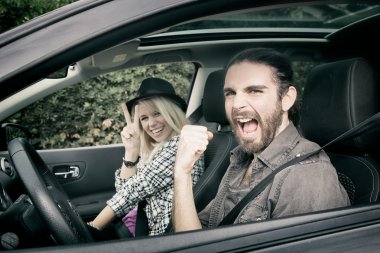 Cars - cool hipster couple driving in new car screaming happy, looking at camera