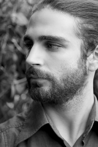 Крупный план портрета молодого человека с бородой, смотрящего в сторону
