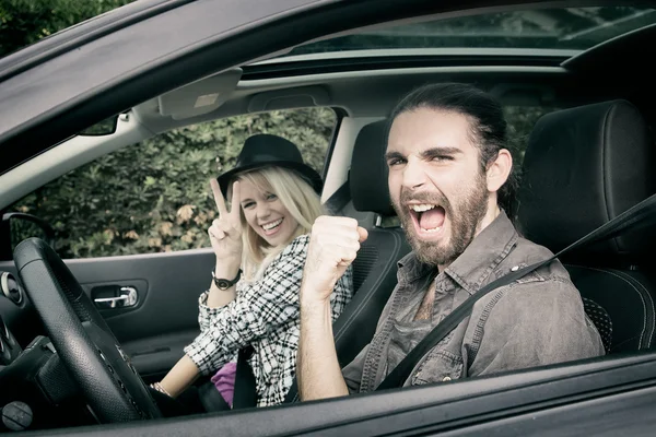 Coches - pareja hipster fresco conducir en coche nuevo gritando feliz, mirando a la cámara — Foto de Stock