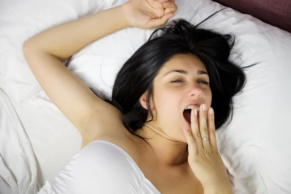 Hermosa mujer en la cama tratando de despertar bostezando y estirando —  Fotos de Stock