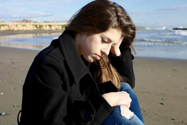 Adolescente triste pensando seduto sulla spiaggia in inverno — Foto Stock