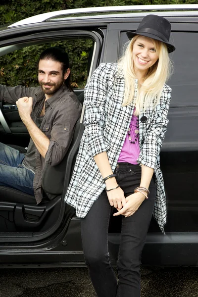 Feliz hipster pareja en frente de coche sonriendo mirando cámara vertical — Foto de Stock