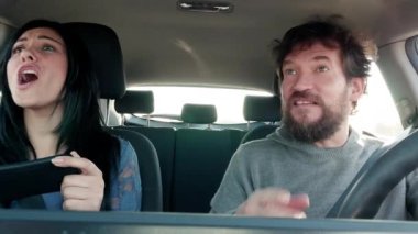 Kadın, erkekler araba kullanırken cep telefonuyla dijital navigatörle yol bulmaya çalışıyor. 