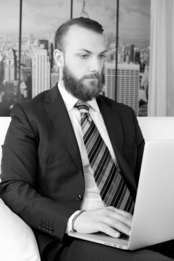 Ofis dizüstü siyah ve beyaz üzerinde çalışan sakallı yakışıklı iş adamı