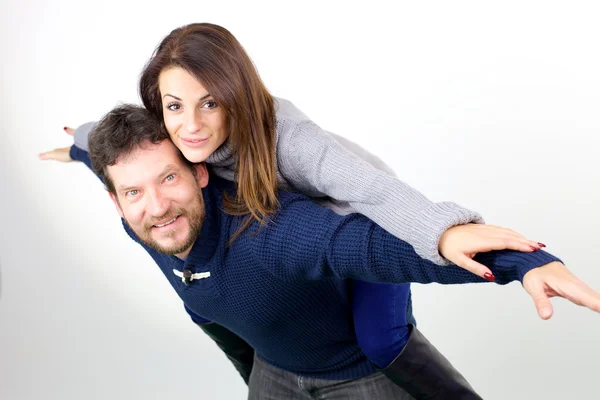 Leuke vrouw paardrijden op de achterkant van vriendje op zoek camera glimlachen geïsoleerd medium shot — Stockfoto