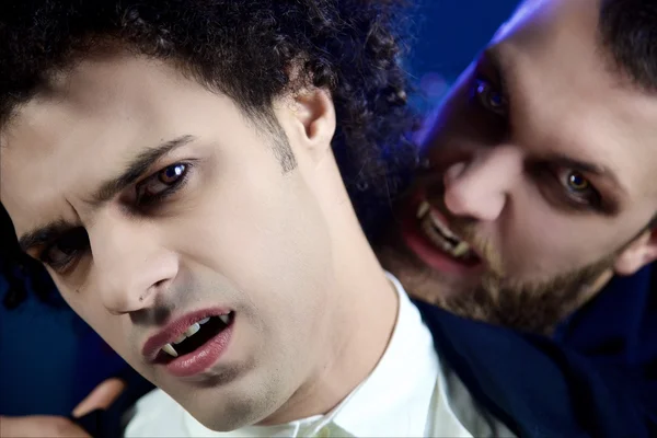 Male vampire attacking other desperate vampire looking camera