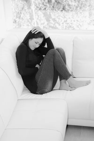 Mujer sintiendo fuerte dolor de estómago sentado en el sofá en casa — Foto de Stock