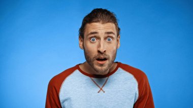 shocked and bearded man looking at camera on blue clipart