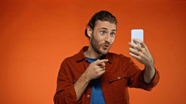 Akıllı telefona bakıp portakalda selfie çeken neşeli bir adam. 
