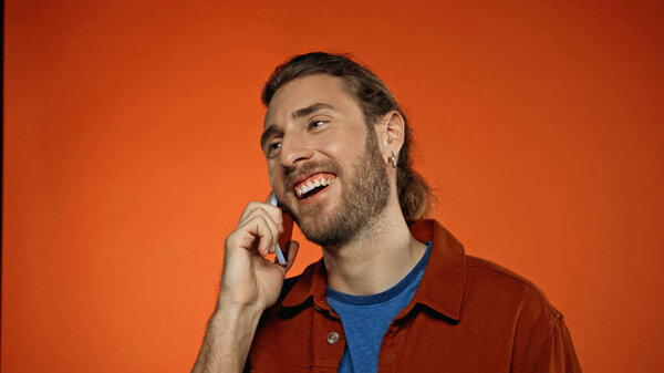 веселый молодой человек разговаривает по мобильному телефону на оранжевый 