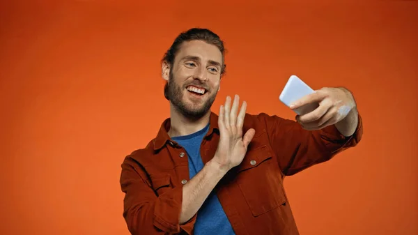 Barbudo Joven Saludando Mano Mientras Tiene Videollamada Naranja — Foto de Stock