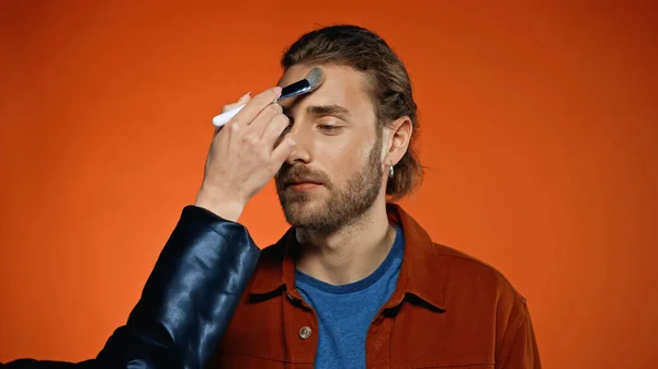 Make Artist Trägt Gesichtspuder Auf Jungen Bärtigen Mann Auf Orange — Stockfoto