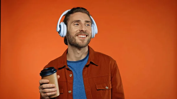 Vrolijke Man Draadloze Hoofdtelefoon Met Papieren Beker Luistermuziek Oranje — Stockfoto