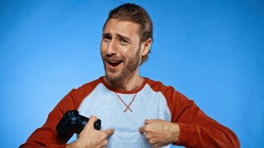 KYIV, UKRAINE - 24 Kasım 2020: şaşırmış adam joystick tutuyor ve mavi kameraya bakıyor 