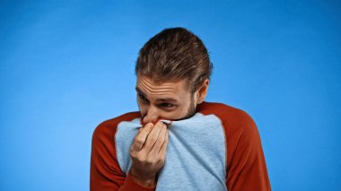 man covering nose with shirt while feeling unpleasant smell on blue clipart