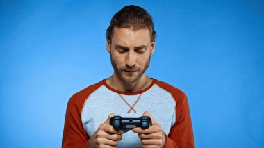 KYIV, UKRAINE - 24 Kasım 2020: sakallı adam elinde joystick ve mavi ile video oyunu oynuyor 