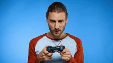 KYIV, UKRAINE - 24 Kasım 2020: elinde joystick tutan ve mavi ile video oyunu oynayan konsantre adam 