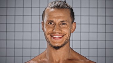 olumlu adam banyodaki bulanık arka planda kameraya bakıyor. 