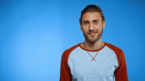 joyful young man smiling on blue background 