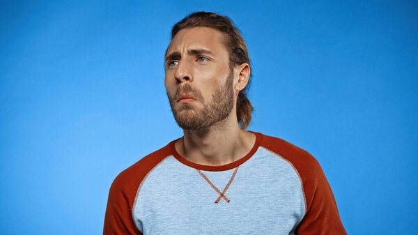 Молодой бородатый человек чувствует неприятный запах на голубом