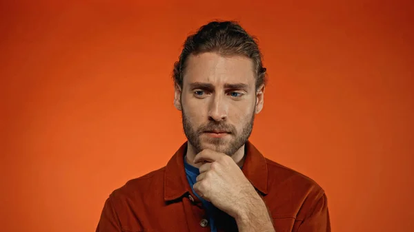 Nachdenklicher Mann Berührt Bart Auf Orangefarbenem Hintergrund — Stockfoto