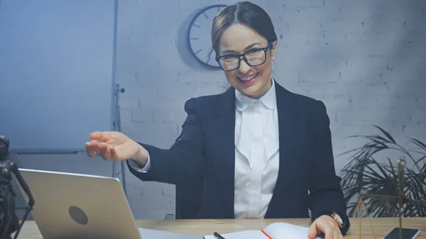 Smiling Insurance Agent Pointing Hand Devices Scales Blurred Foreground — Stock Photo, Image